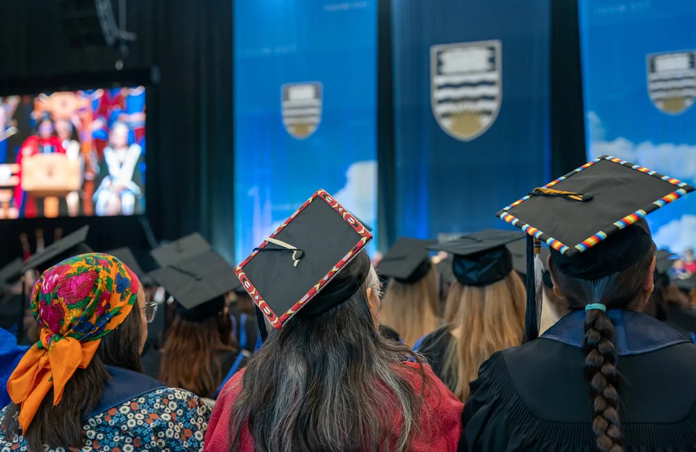 Nsyilxcn students wearing decorative motorboard hats at graduation