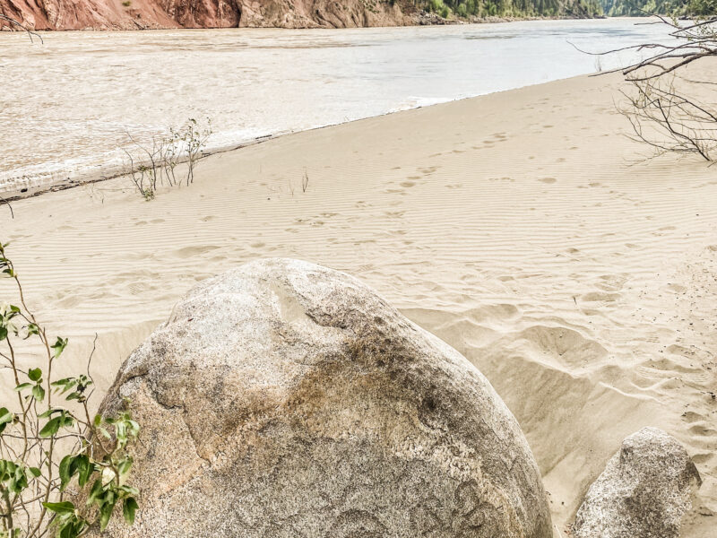 A rock in front of a river with Indigenous writing on it.