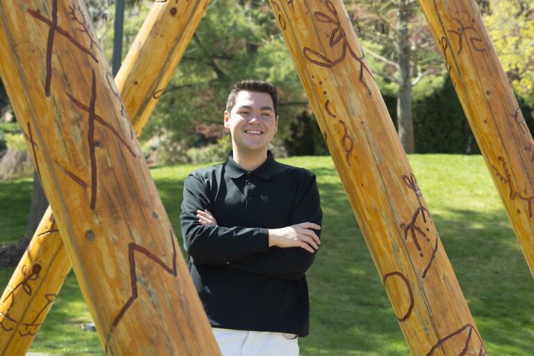 Noah standing under the Story Poles at UBC Okanagan