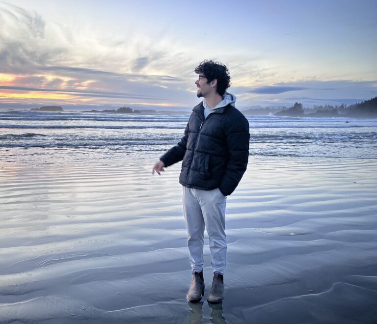 Hammad stands on the shore by the ocean.