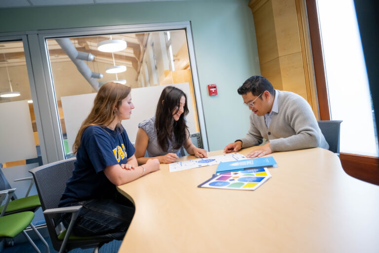 An advisor and two students reviewing the student guide